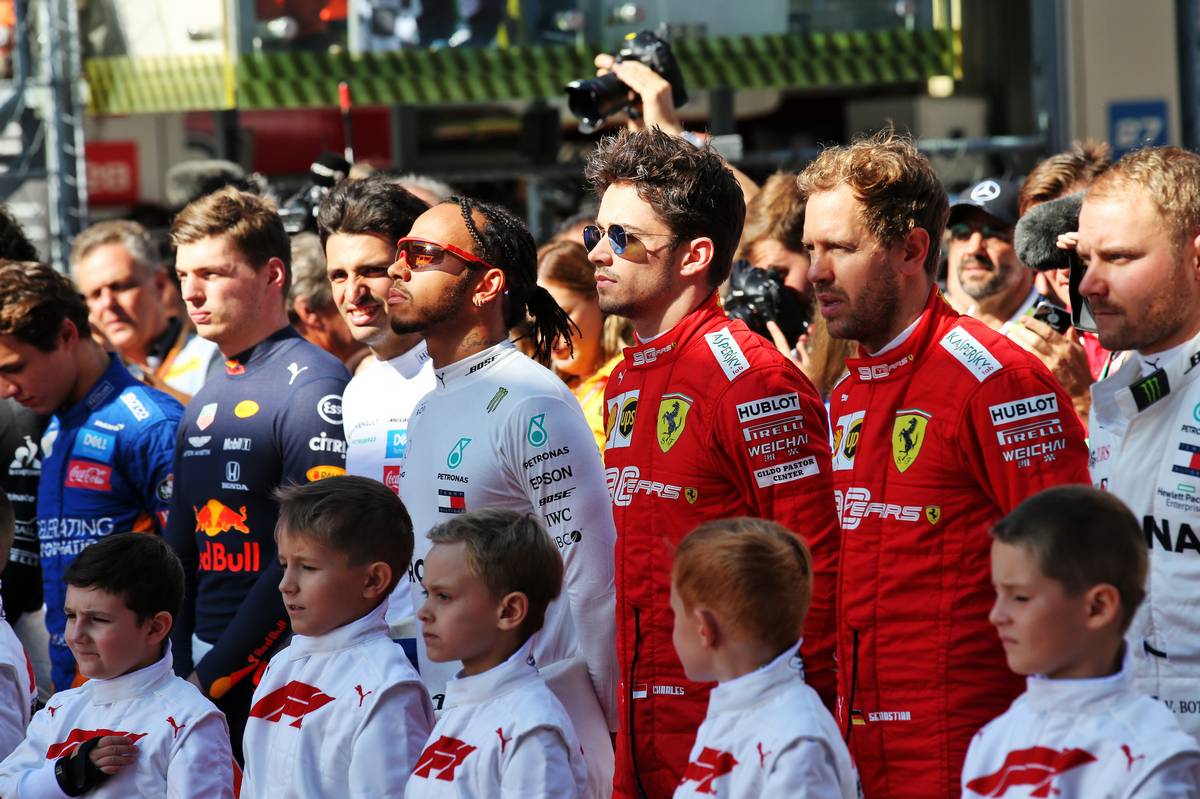 Lewis Hamilton (GBR) Mercedes AMG F1; Charles Leclerc (MON) Ferrari; and Sebastian Vettel (GER) Ferrari, as the grid observes the national anthem.