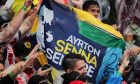 An Ayrton Senna banner with fans at the podium.