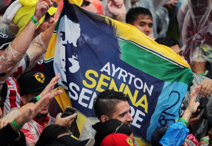 An Ayrton Senna banner with fans at the podium.