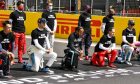 Drivers on the grid take a knee before the start of the race.